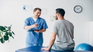 Chiropractor Holding Pen Talking with His Patient