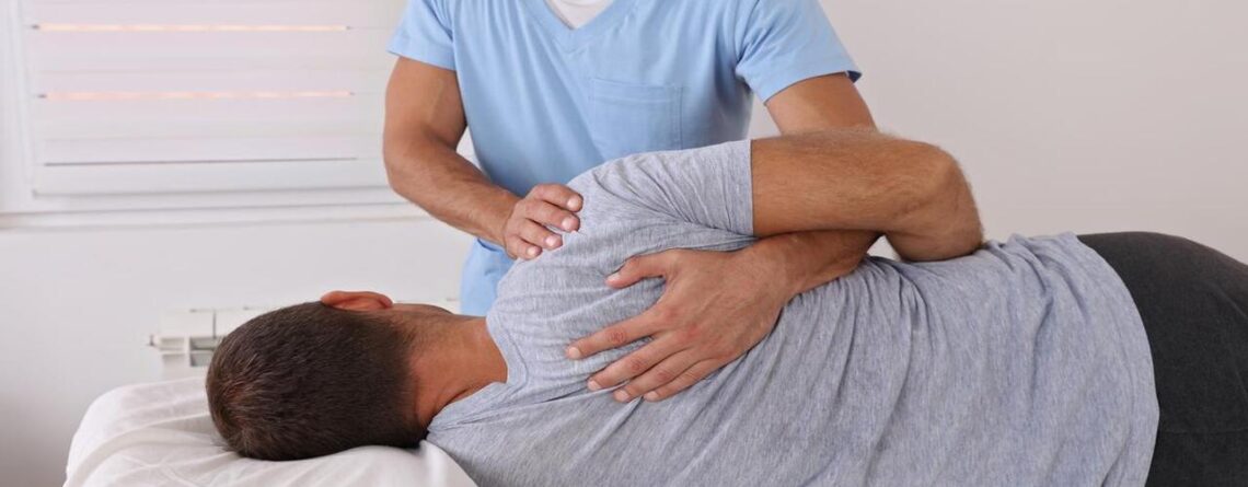 Male Chiropractor Adjusting the Back of His Patient